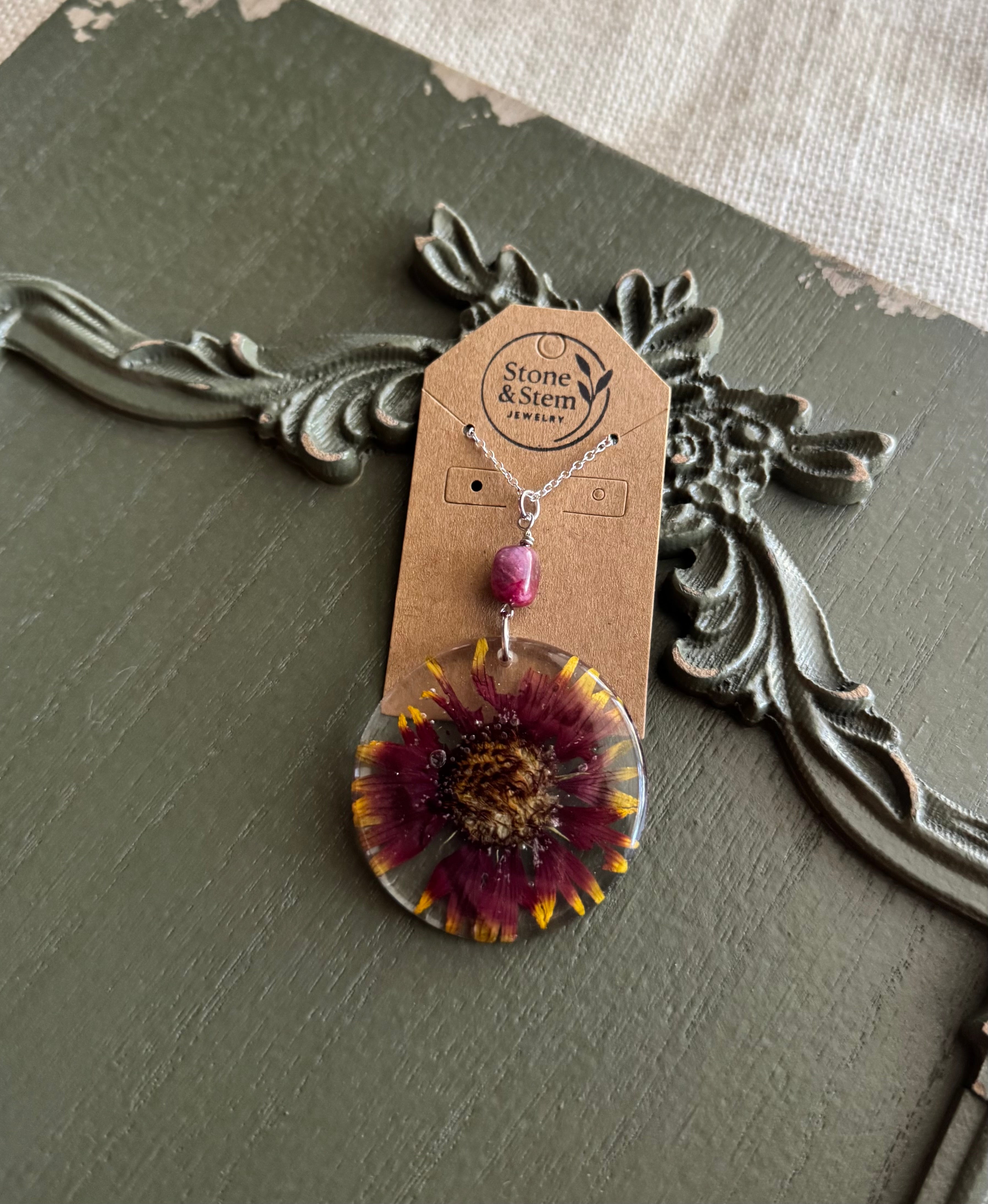 Blanket flower preserved in clear round resin pendant necklace with pink stone bead on silver-tone chain, displayed on Stone & Stem Jewelry card