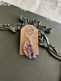 Purple wildflowers preserved in clear teardrop resin pendant necklace on silver-tone chain, displayed on Stone & Stem Jewelry card