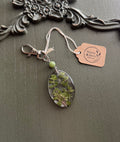 Thyme sprigs preserved in clear oval resin keychain with green stone bead and silver-tone lobster clasp, displayed on Stone & Stem Jewelry tag