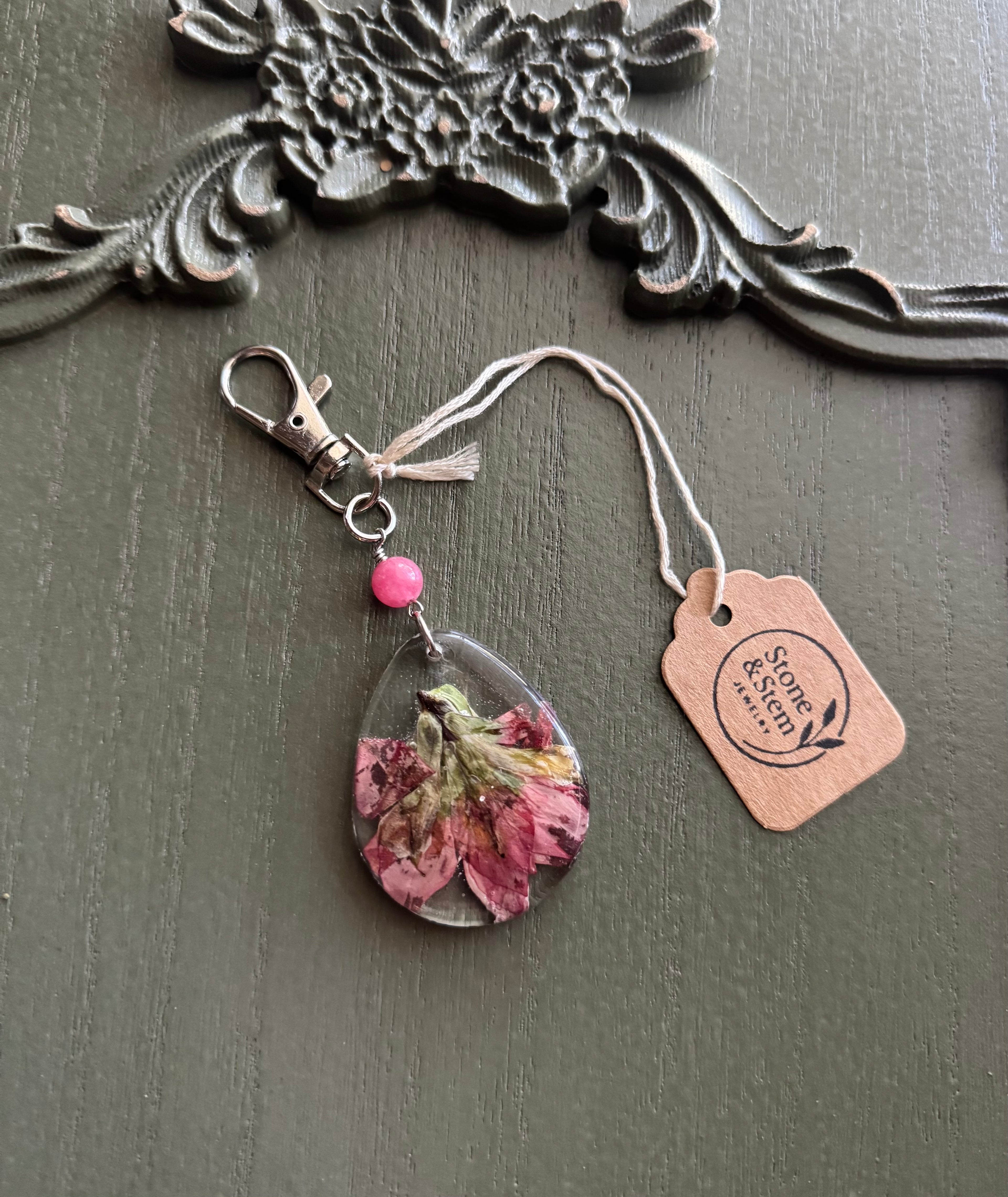Indian Paintbrush wildflower preserved in clear teardrop resin keychain with pink stone bead and silver-tone lobster clasp, displayed on Stone & Stem Jewelry tag