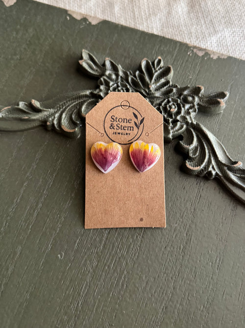 Pair of heart-shaped resin stud earrings with pressed purple and yellow blanket flower petals on a Stone & Stem Jewelry kraft card