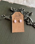 Pair of small white oval resin stud earrings with pressed pink flower petals on a Stone & Stem Jewelry kraft card