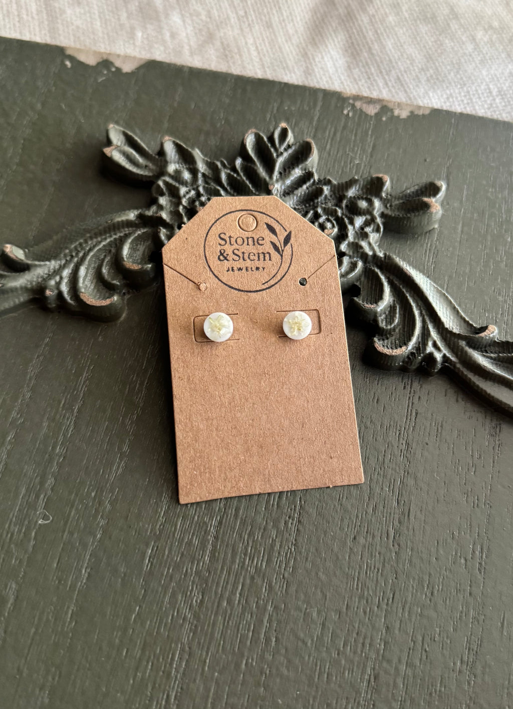 Pair of small white round resin stud earrings with pressed white flowers on a Stone & Stem Jewelry kraft card