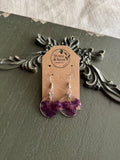 Pair of clear round resin drop earrings filled with deep purple myrtle flower petals on 925 sterling silver ear wires on a Stone & Stem Jewelry kraft card