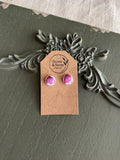 Pair of small domed white round resin stud earrings with pressed magenta myrtle flower petals on a Stone & Stem Jewelry kraft card